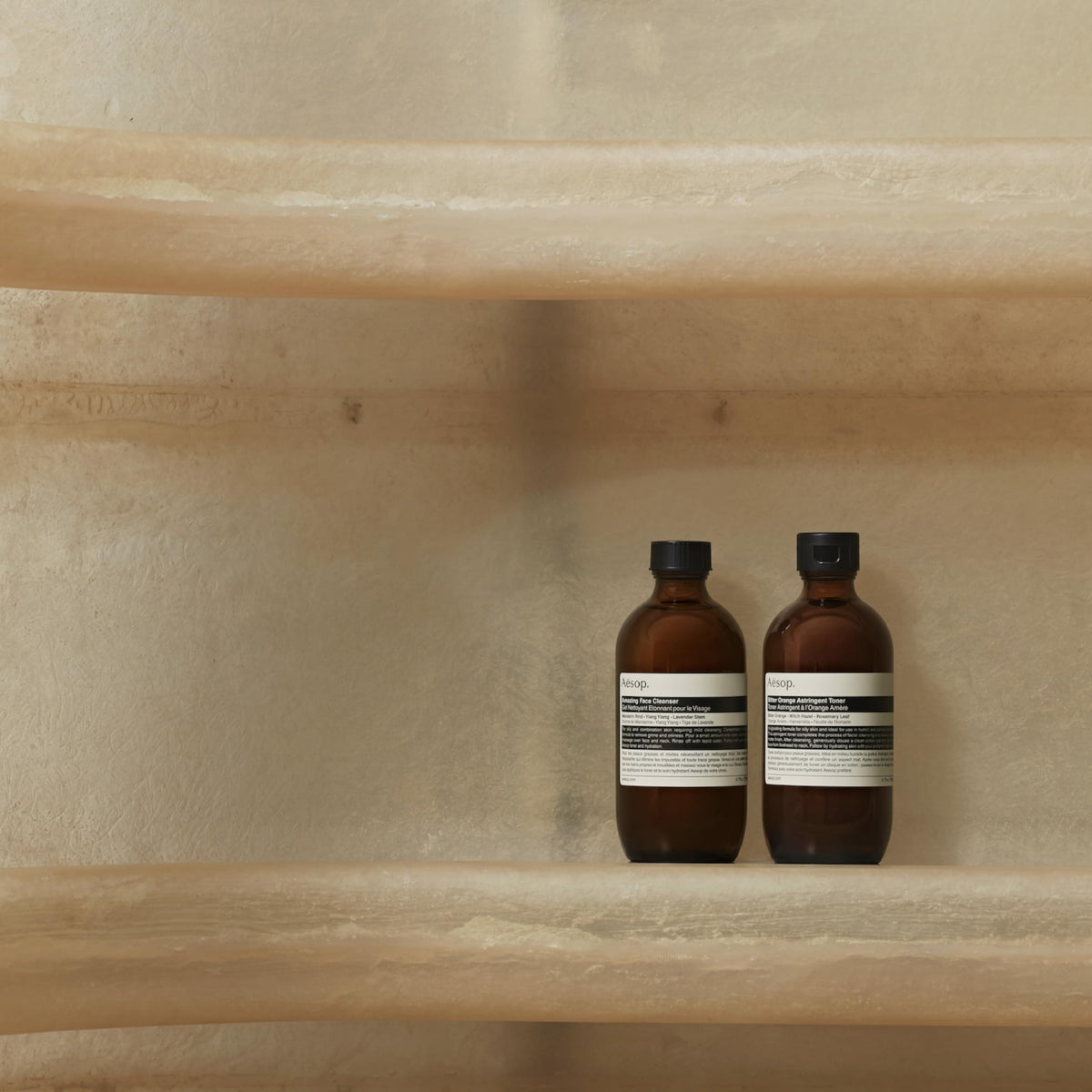 Hand holding Aesop 100 mL travel bottle illustrating convenient travel benefit