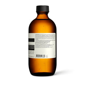 Aesop bottle held in hand to show 200 mL size and travel practicality