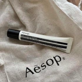 Aesop lip balm held in hand to show compact 0.3 fl oz scale and easy on‑the‑go convenience