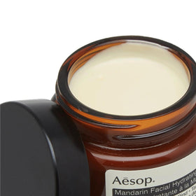 Aesop jar beside mandarin and lemon rinds, highlights natural citrus ingredients