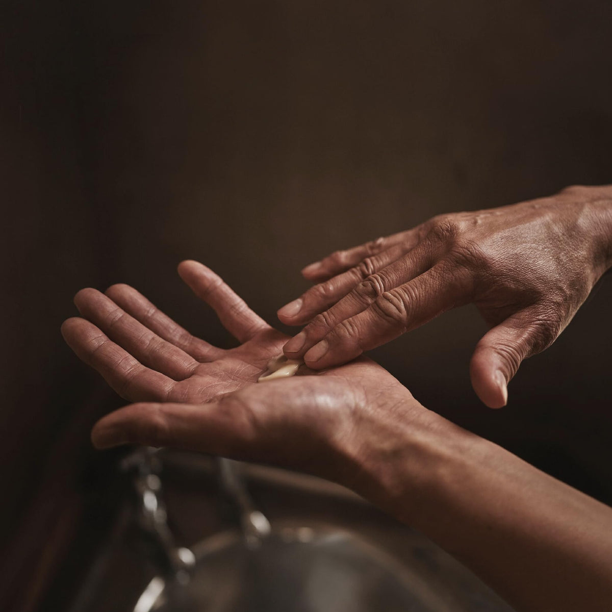 Hand applying Aesop balm to forearm showing quick absorption and visible smoothing benefit