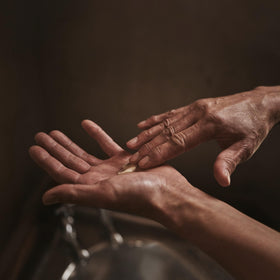 Hand applying balm to elbow, demonstrates Aesop targeted relief for dry areas