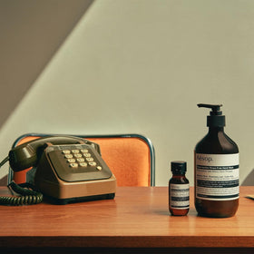 Aesop tube beside a passport to show 1.7 oz travel-friendly scale for flights and commuting