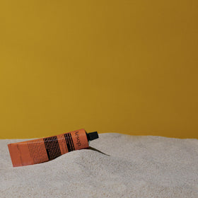 Aesop tube next to passport and keys illustrating travel-friendly 100 mL size