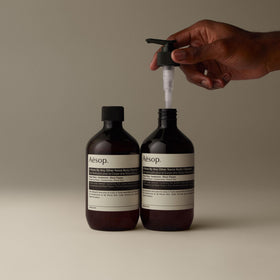 Aesop bottle in shower setting evoking aromatherapy and warm scent
