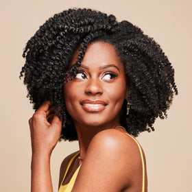 African Pride cream being smoothed into curls for improved manageability