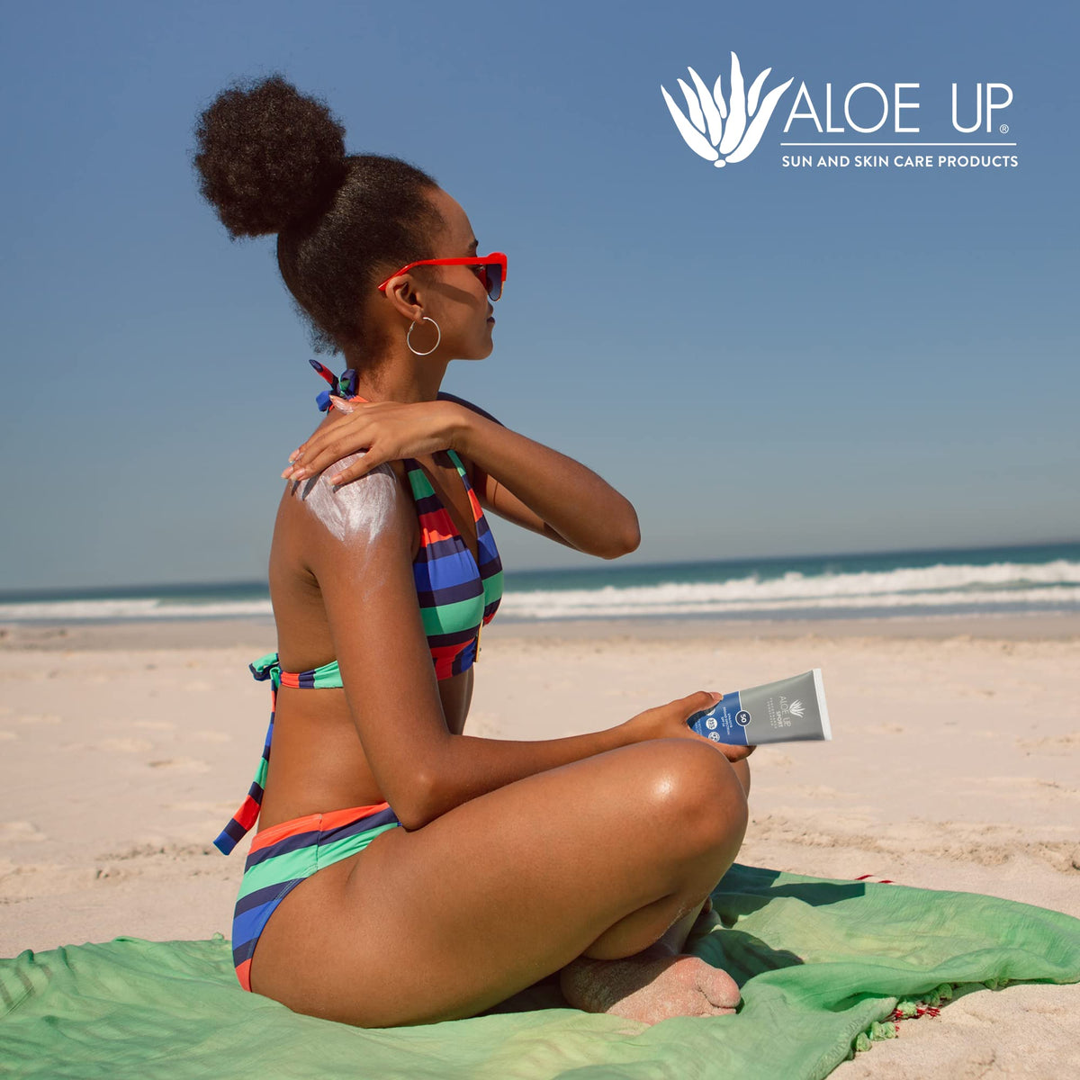 ALOE UP tube on beach towel portraying outdoors sun-care convenience
