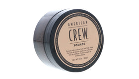 Hands applying American Crew pomade to hair demonstrating easy spread and control