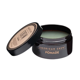 American Crew pomade texture close-up on fingertips, demonstrating smooth, spreadable consistency