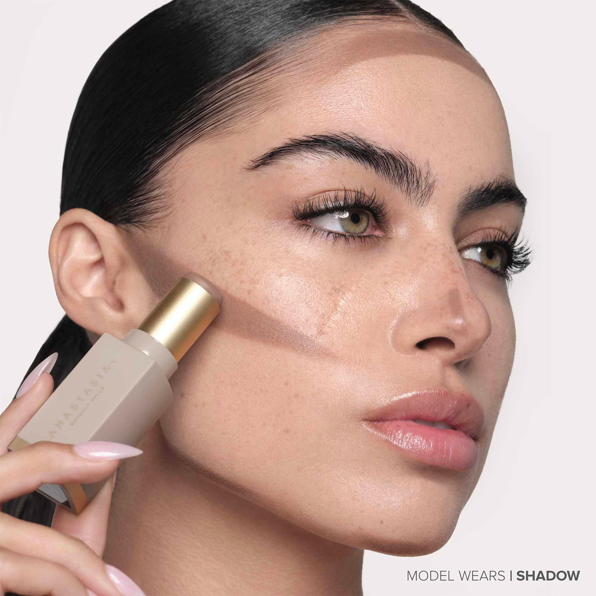 Anastasia Beverly Hills applying stick to cheek, helps create instant dimension benefit