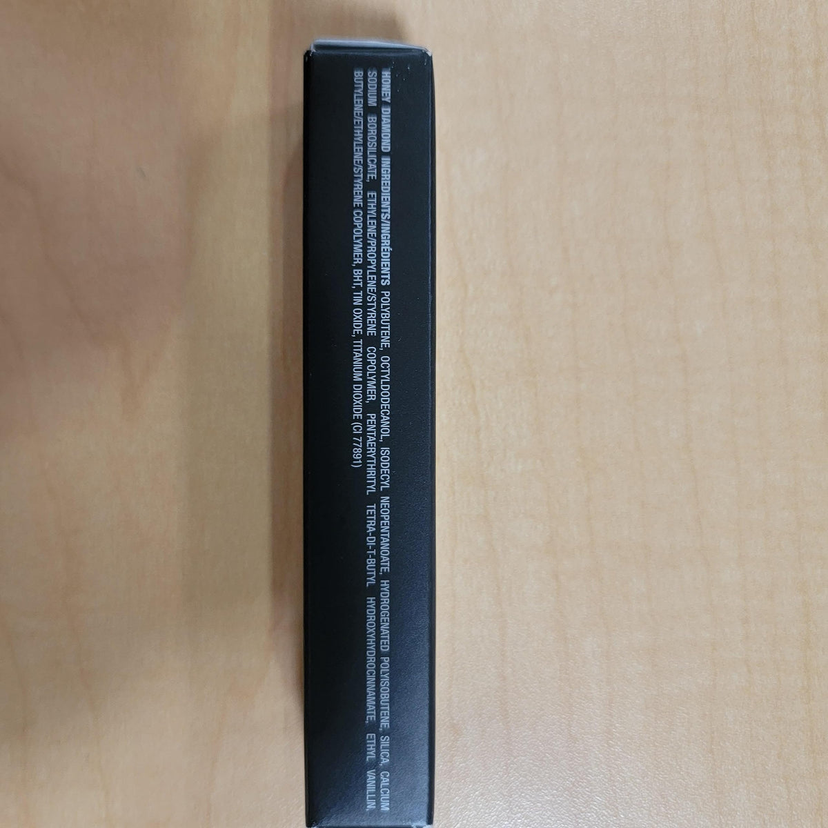 Anastasia Beverly Hills gloss next to coin to display compact size and travel-friendly fit