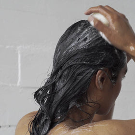 ATTITUDE shampoo bar in hand creating foam on wet hair, convenient travel benefit