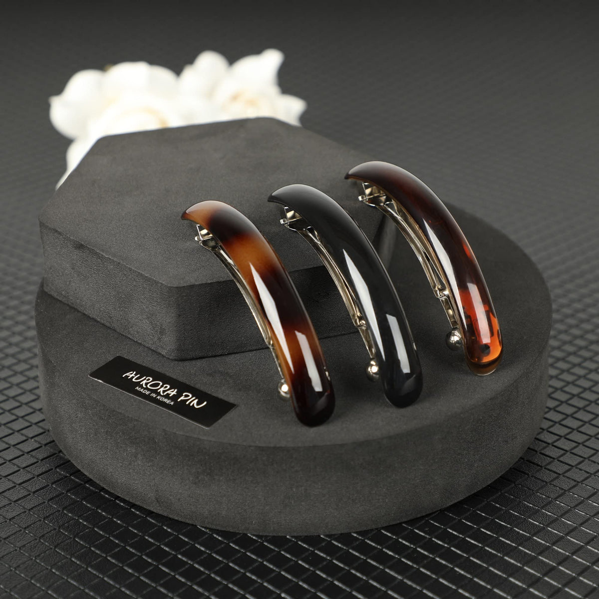 AURORA PIN clip displayed on a desk beside fashion items showing stylish versatility