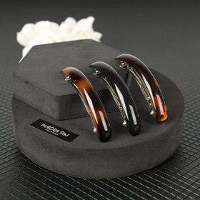 AURORA PIN clip displayed on a desk beside fashion items showing stylish versatility