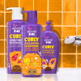 Aussie leave-in detangler spray being applied to damp curls for manageable hair