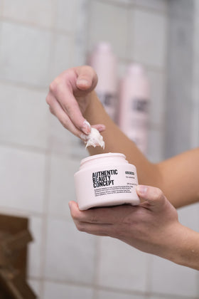 Authentic Beauty Concept applying mask to hair strands for deep conditioning benefit