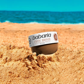 Babaria bottle in a sunny beach lifestyle scene suggesting a tropical tanning vibe