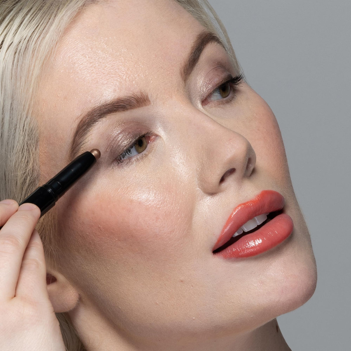 Billion Dollar Beauty applying shimmer stick on eyelid demonstrating instant brightening effect