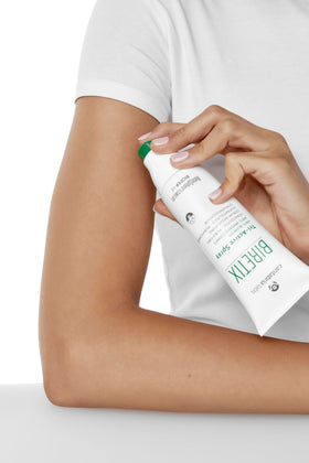 Biretix Tri-Active Spray next to hand for scale showing travel-friendly size