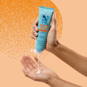 Blue Lizard bottle near water splashes demonstrating 80-minute resistance