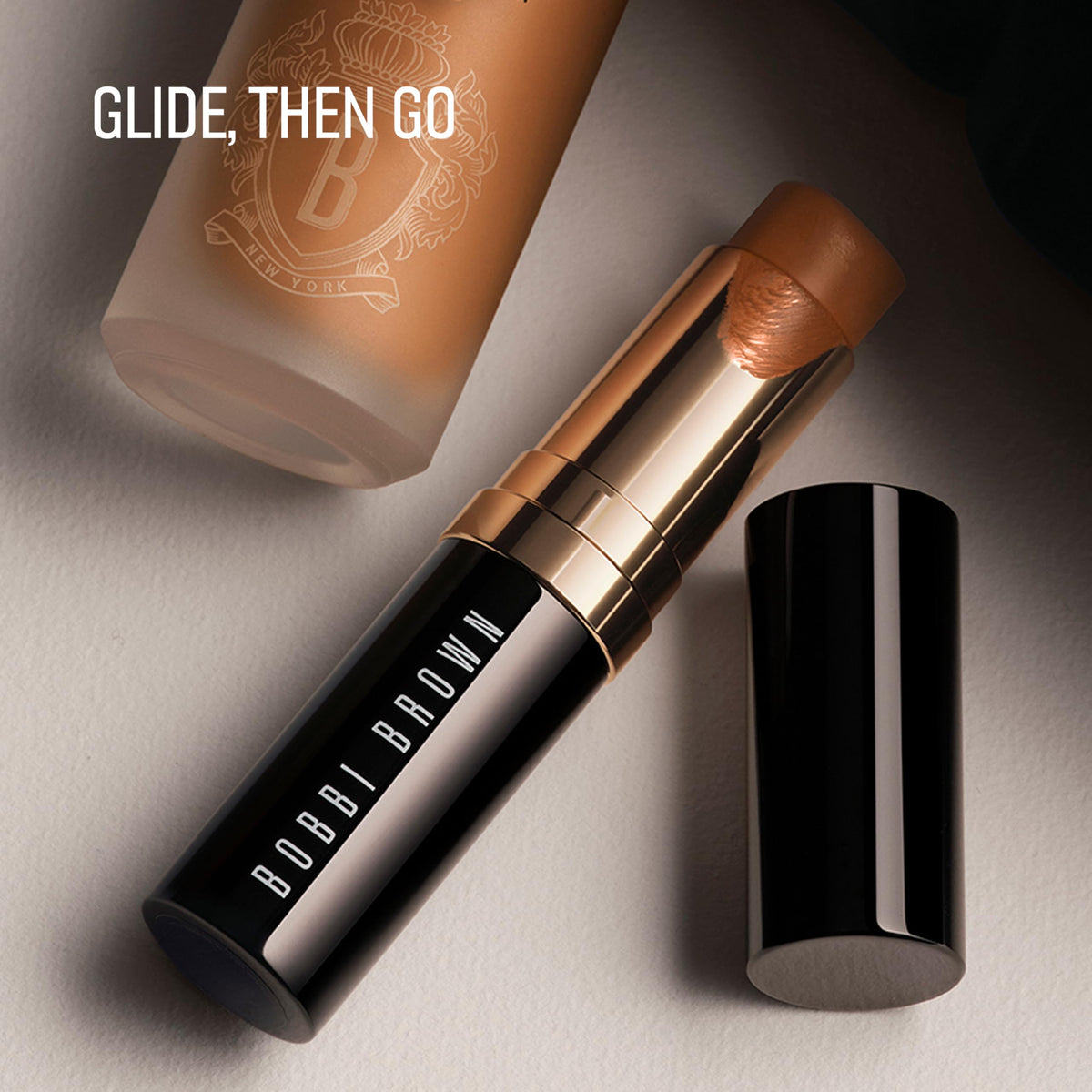 Bobbi Brown foundation stick next to coin showing compact size and travel-ready benefit