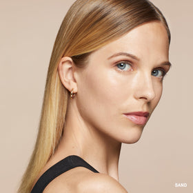 Bobbi Brown concealer placed beside foundation tube showing layering use