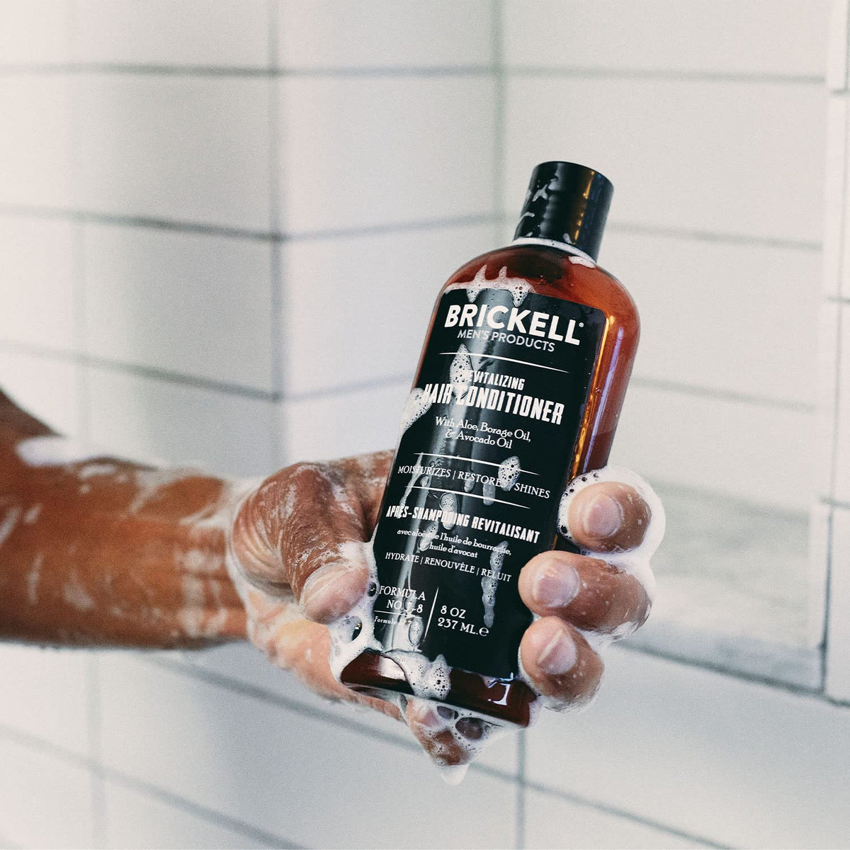 Brickell 8 oz conditioner shown beside razor to illustrate size and portability