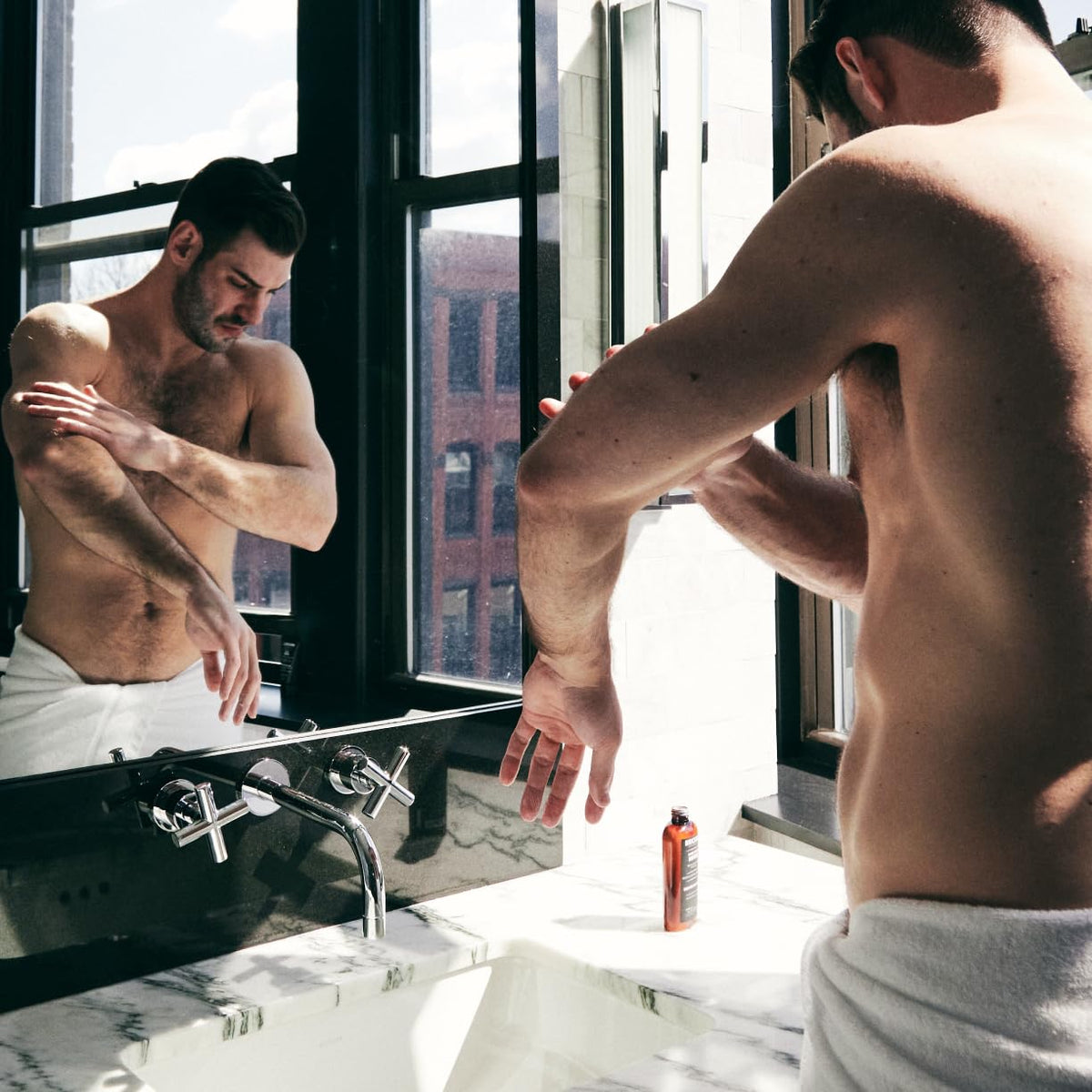 Brickell Men's Products man applying lotion to arm showing ease of use and skin comfort