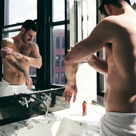 Brickell Men's Products man applying lotion to arm showing ease of use and skin comfort