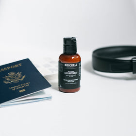 Brickell Men’s tube beside passport showing 2 oz travel size benefit fits luggage