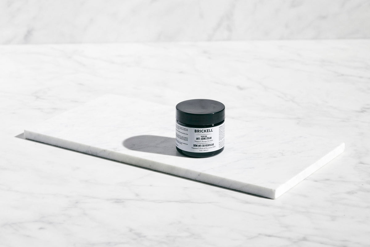Brickell cream on hand being applied to face demonstrating easy spreadability benefit