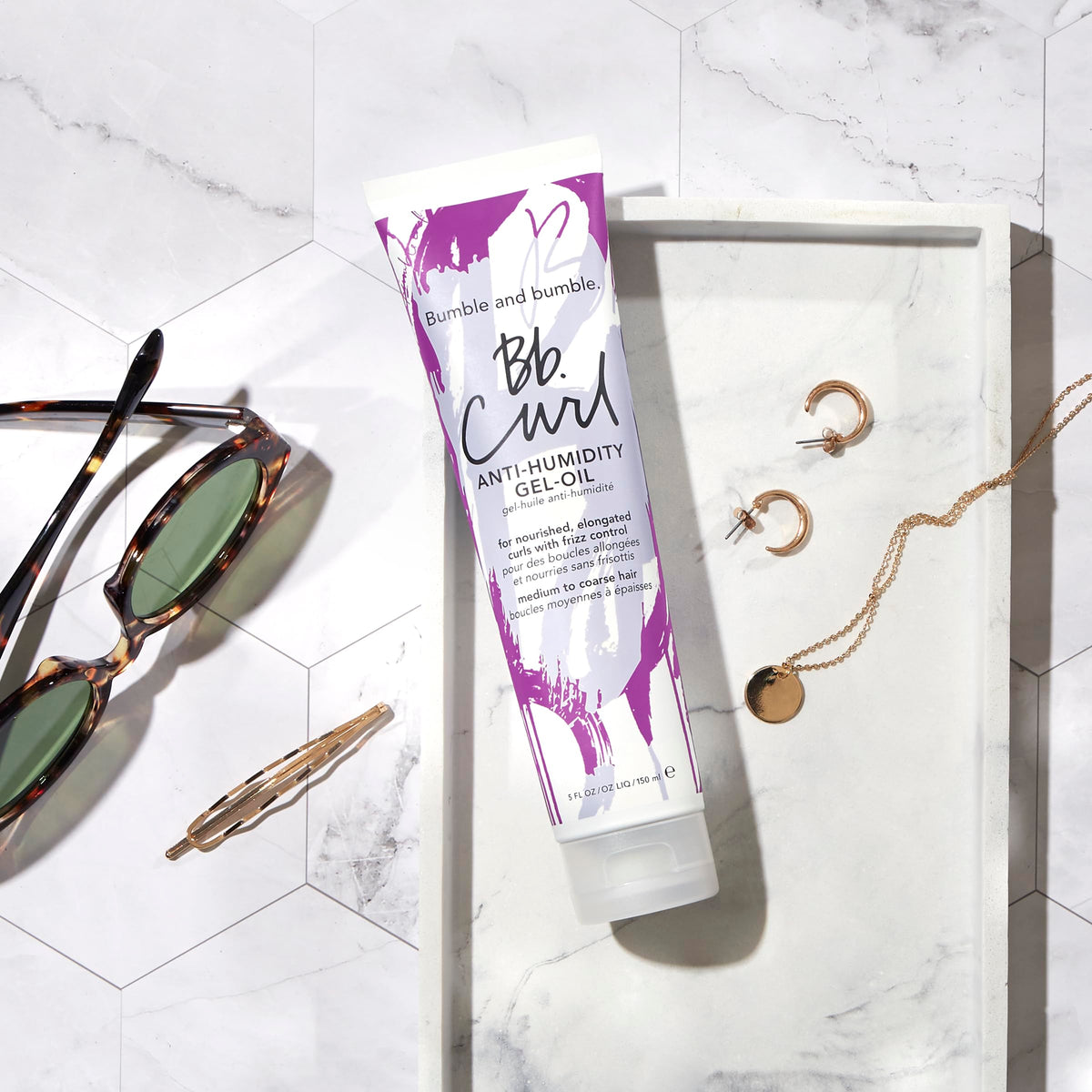 Bumble and bumble bottle beside a hand to show 5 fl oz scale and travel convenience