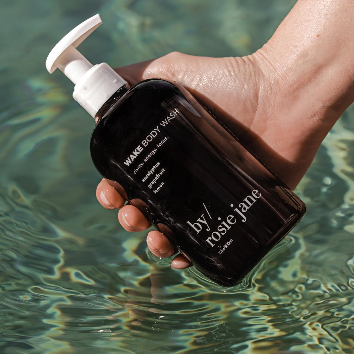 By Rosie Jane 350ml Wake bottle beside hand to show true size and travel-friendly benefit