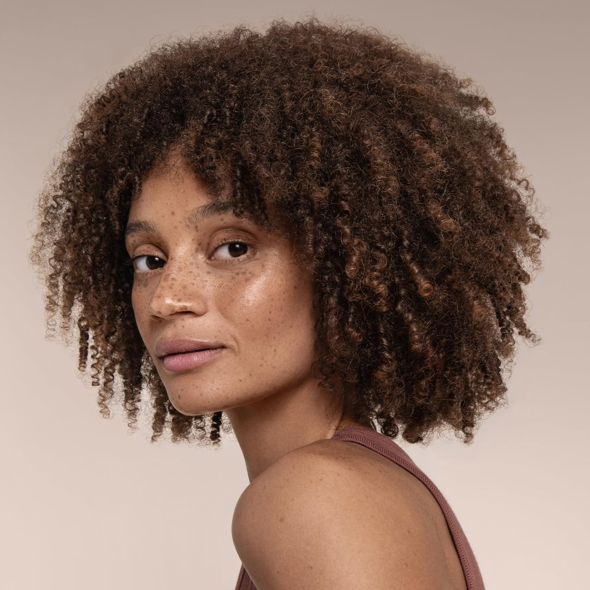 Model spraying Cantu on curly hair to refresh and redefine curls