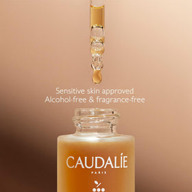 Caudalie 15 mL bottle next to fingers showing compact travel-friendly size benefit
