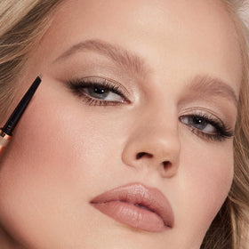 Charlotte Tilbury Brow Cheat in-use applying strokes at mirror for everyday shaping