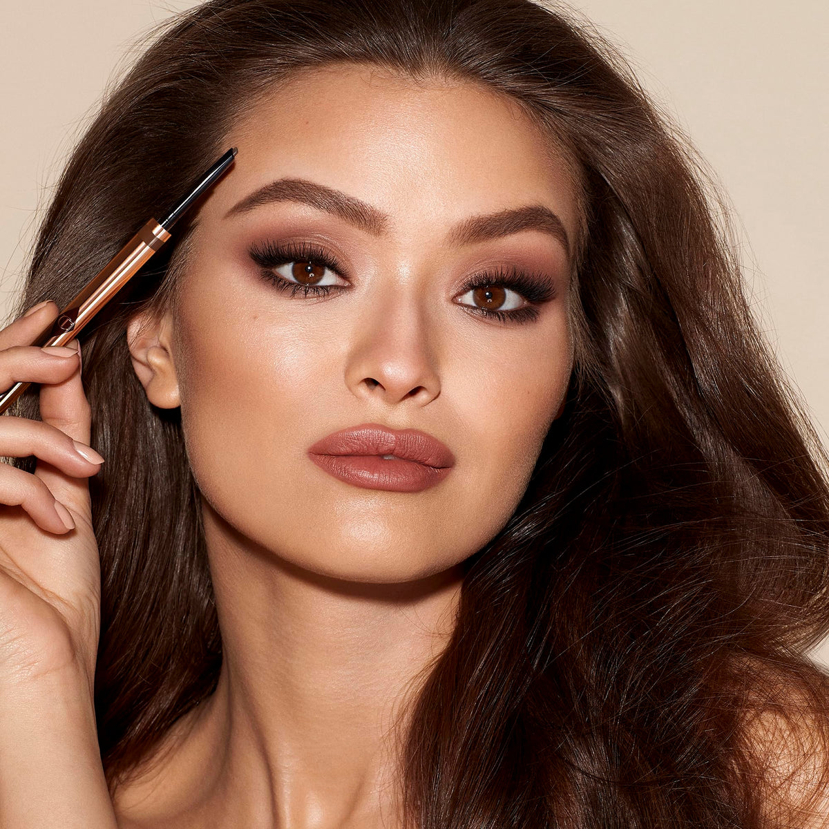 Charlotte Tilbury pencil held in hand to show scale and travel-friendly size