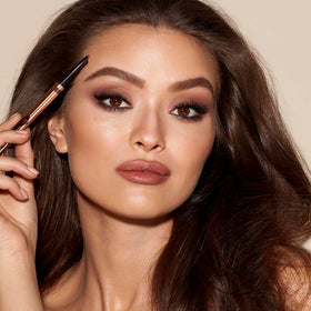 Charlotte Tilbury pencil held in hand to show scale and travel-friendly size