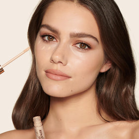Charlotte Tilbury model applying concealer under eye for visible lift and brightness