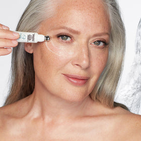 Applying Charlotte Tilbury serum under eye with metal tip to reduce puffiness and smooth skin
