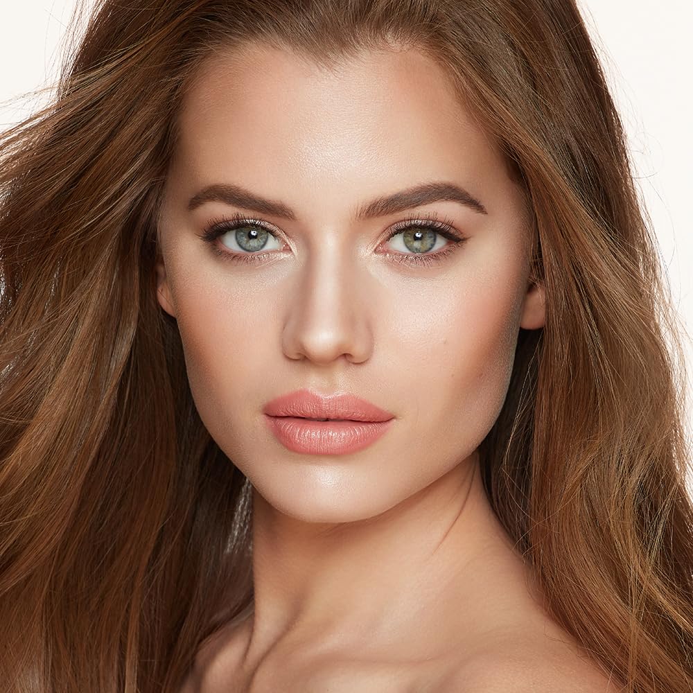 Charlotte Tilbury brush applying highlight to cheek demonstrating natural luminous finish