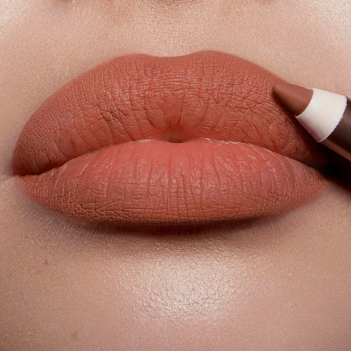 Charlotte Tilbury model applying Hot Gossip to lips showing reshaped fuller look