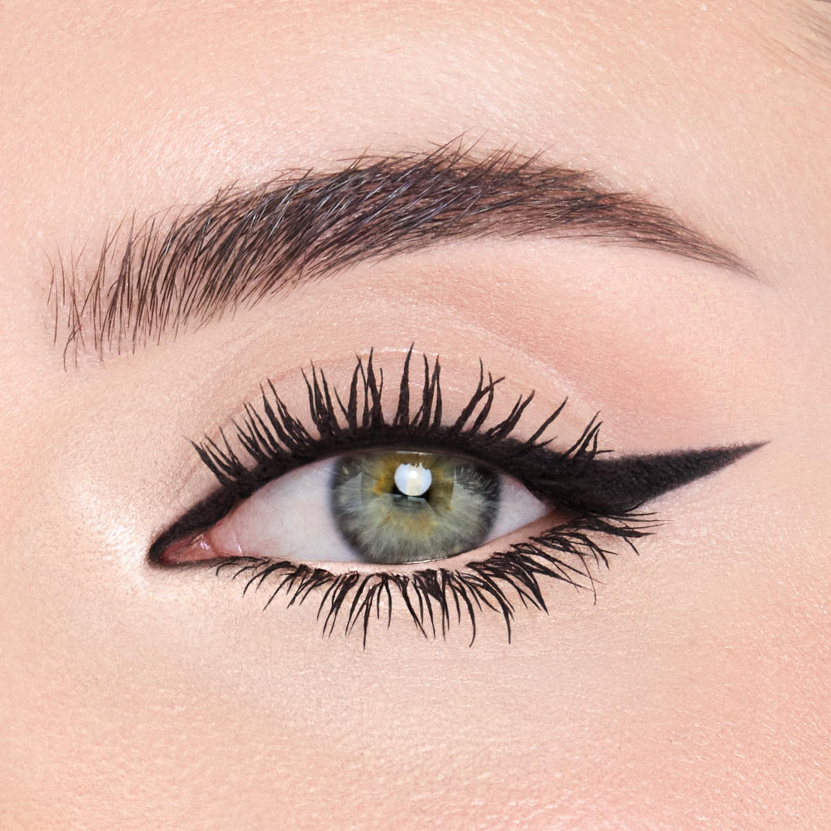 Model applying Charlotte Tilbury liner to inner corner to visibly open eyes