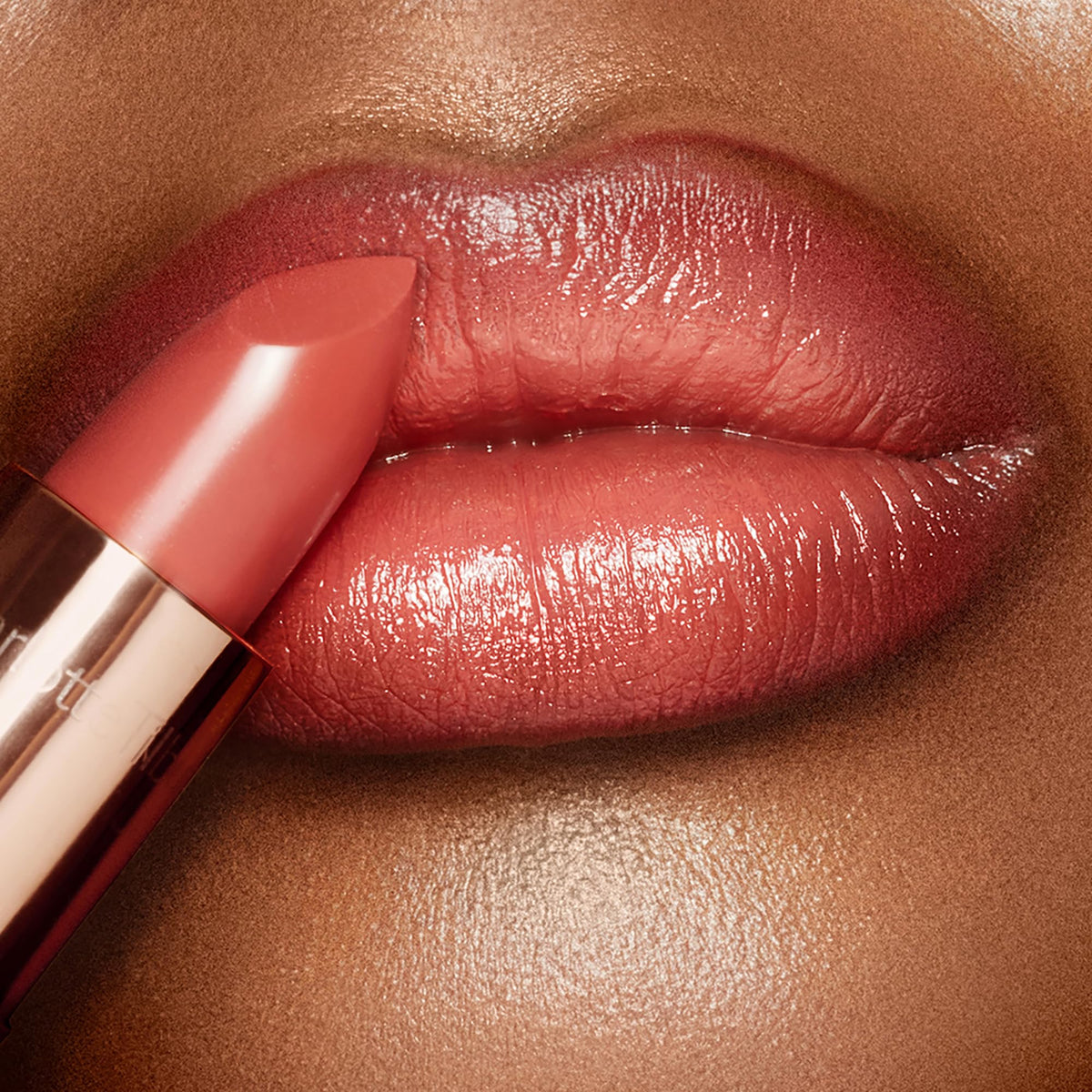 Charlotte Tilbury lip swatch on model demonstrating Coral Kiss wearable coral and brightening effect