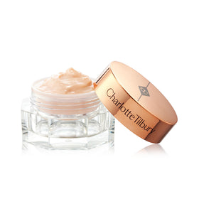 Charlotte Tilbury 15ml tube next to everyday items showing compact travel-friendly size