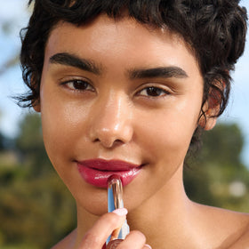 Clarins lip oil balm beside fingertip to show size and portable 0.1 oz convenience