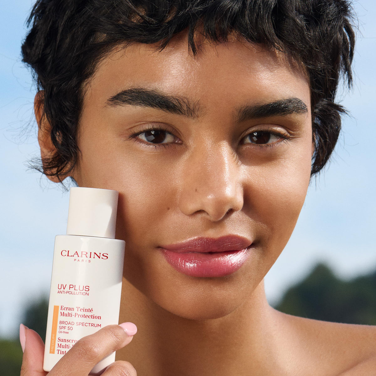 Clarins UV Plus beside a credit card showing compact travel-friendly size