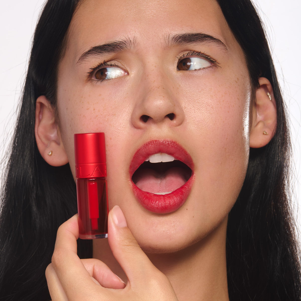 Clarins tube next to coin to show 0.2 fl oz size and portability