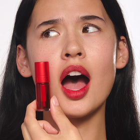 Clarins tube next to coin to show 0.2 fl oz size and portability