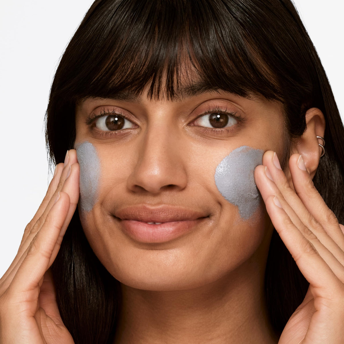 Clinique massaging scrub on cheek demonstrating exfoliation to smooth and refine skin surface